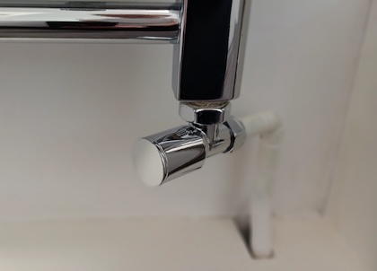 A manual valve attached to a heated towel rail. The cap on the valve doesn’t have any text or numbers on it.