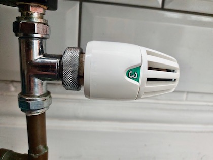 A thermostatic radiator valve attached to a radiator pipe. The valve is set to show the number '3'.