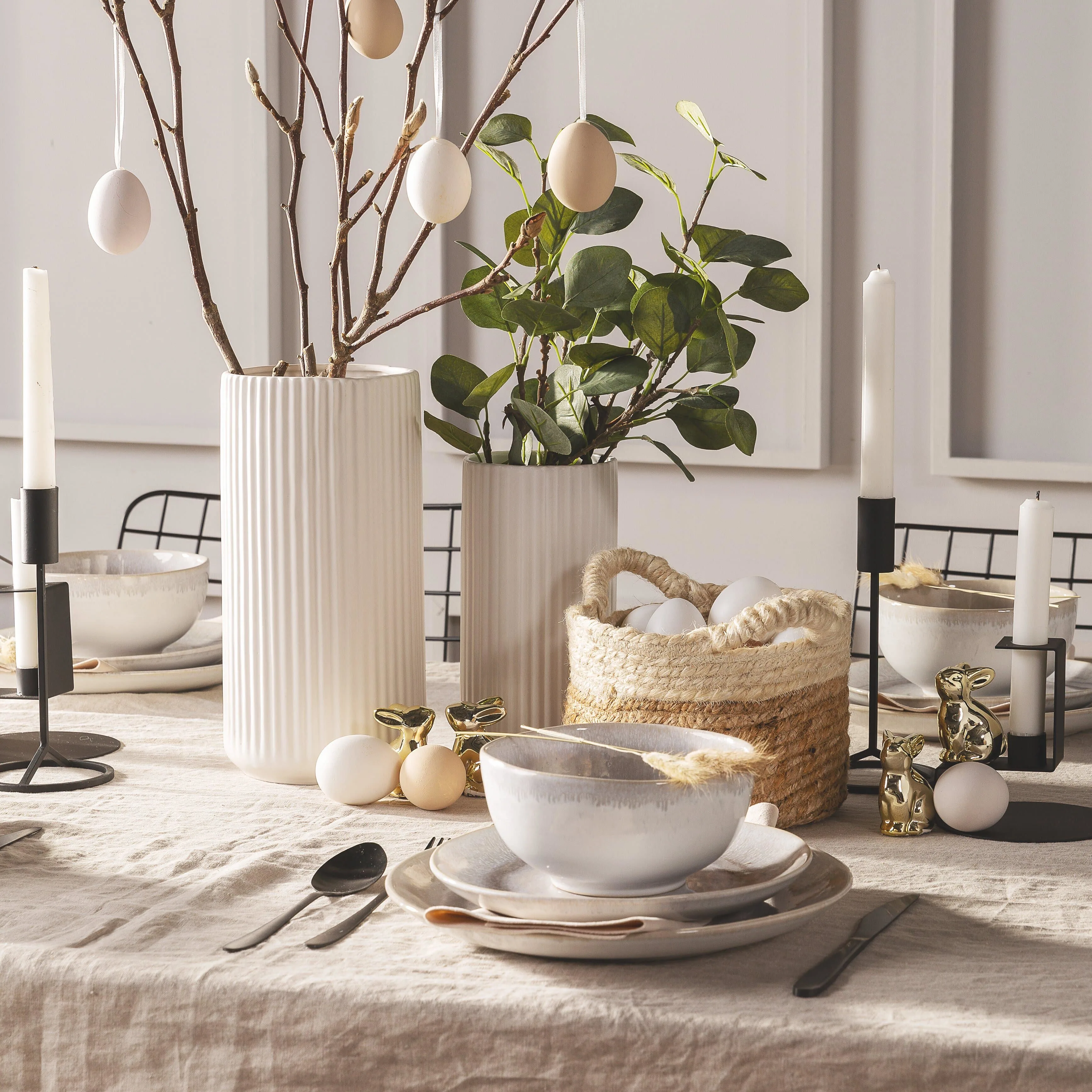 Helle Tischdeko für Ostern mit Ostereiern, goldenen Dekohäschen und Frühlingsblumen