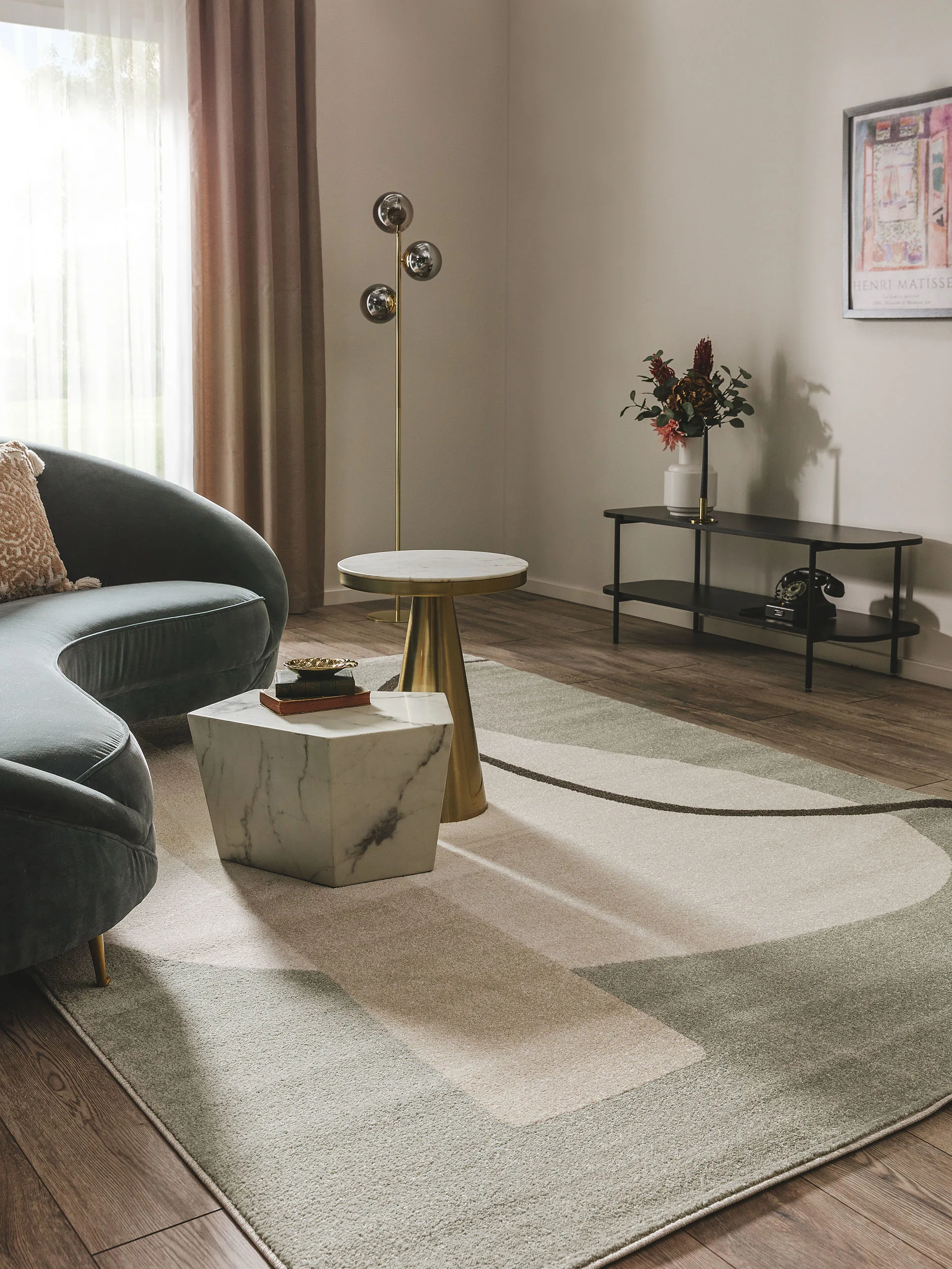 Edel und modern eingerichtetes Wohnzimmer mit Sofa in organischer Form, Marmor-Couchtisch und goldener Stehlampe im Industrial Chic