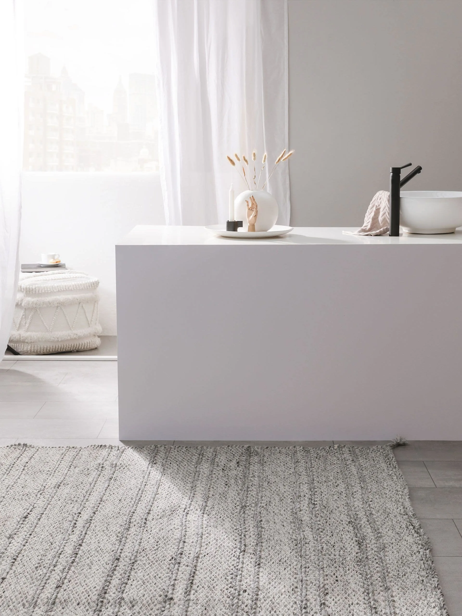 Minimalistisches Badezimmer mit Tageslicht mit moderner Waschbeckenarmatur in Weiß und einem großen, hellen Teppich