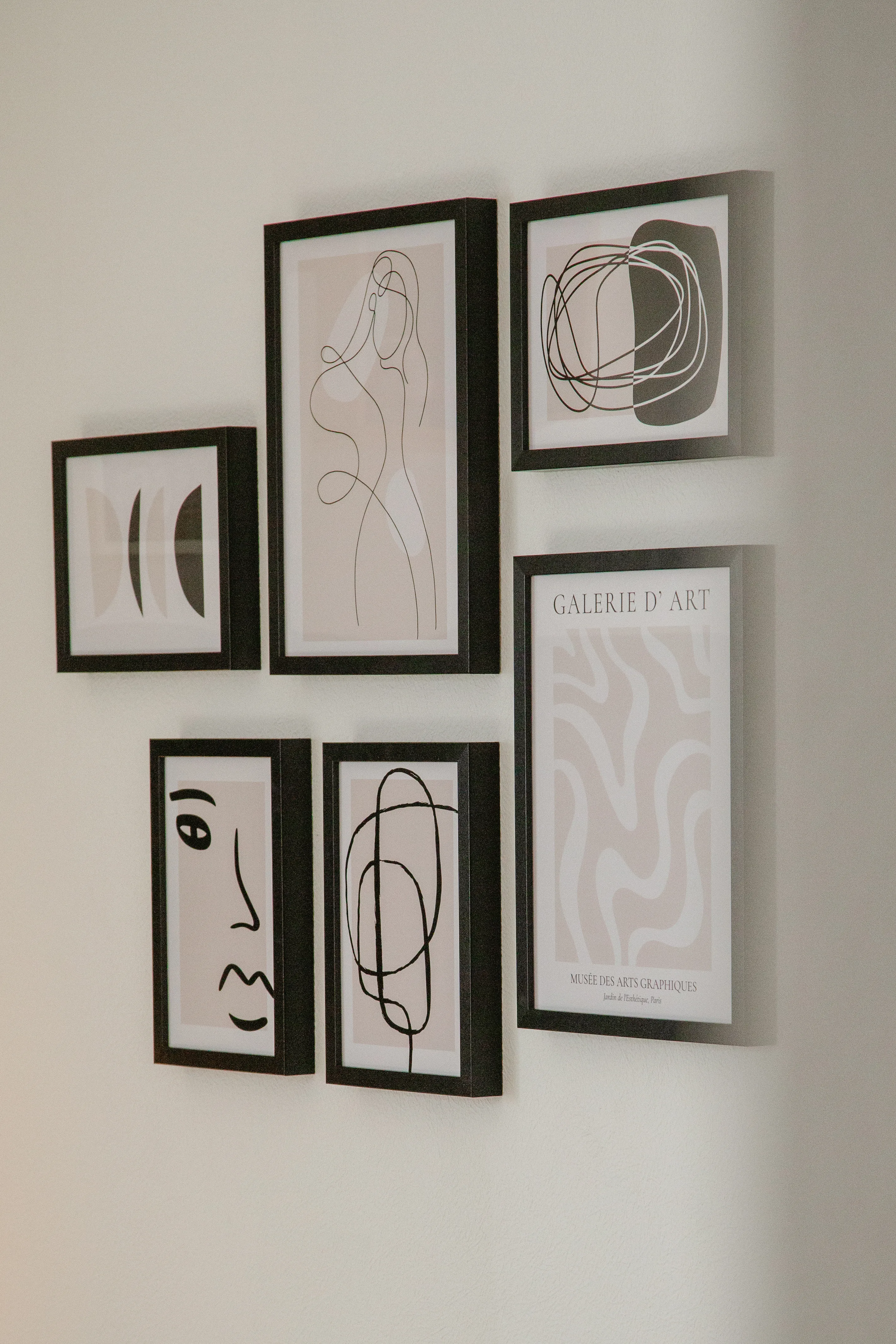 Nahaufnahme von modernen Bildern mit klaren, minimalistischen Linien in schwarzen Bilderrahmen an der Wohnzimmerwand