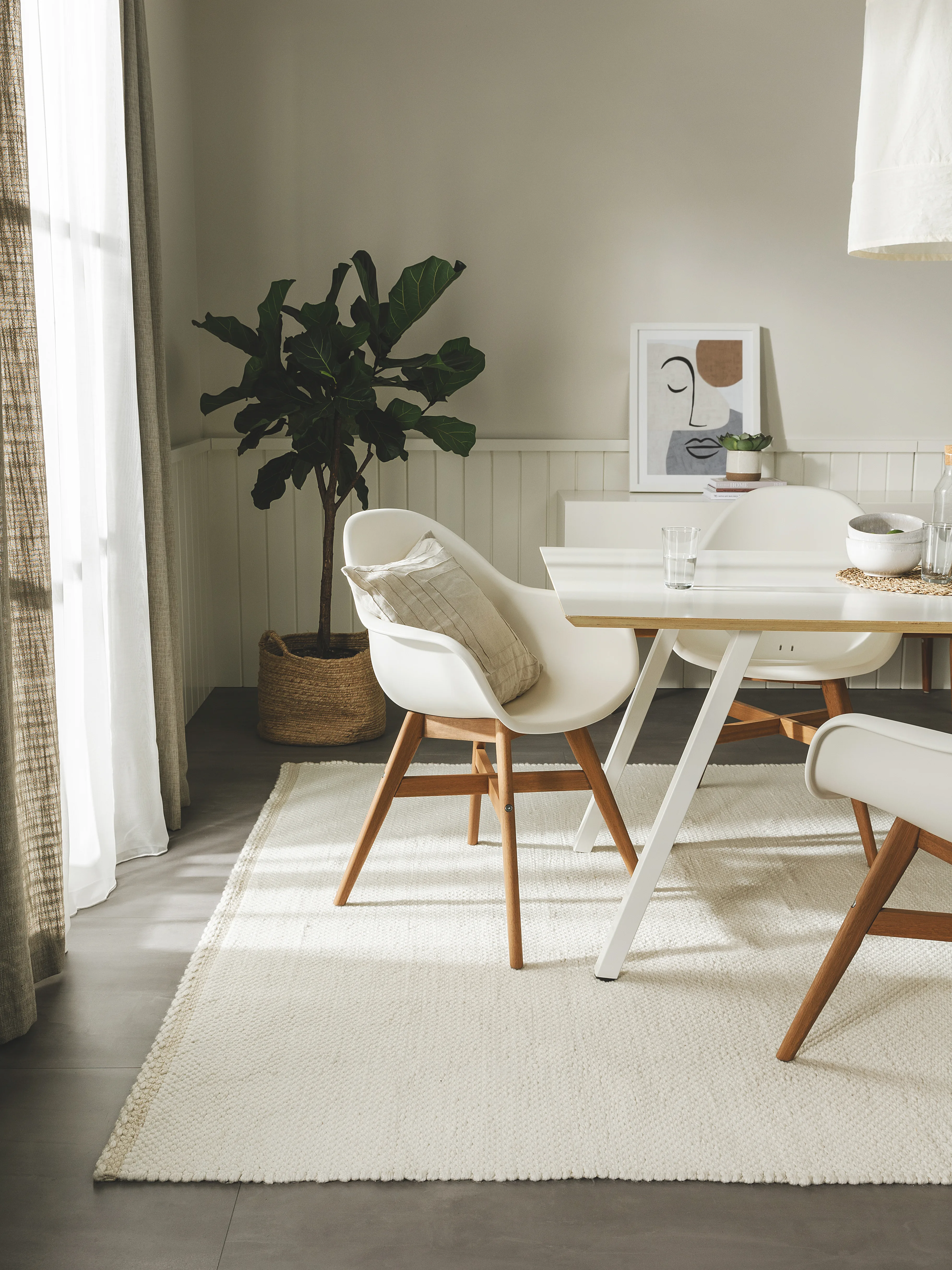 Helles Esszimmer im minimalistischen Skandi Look mit weißem Tisch, weißen Stühlen und einem weißen Flachgewebeteppich, der mit dem Product Green Award ausgezeichnet ist