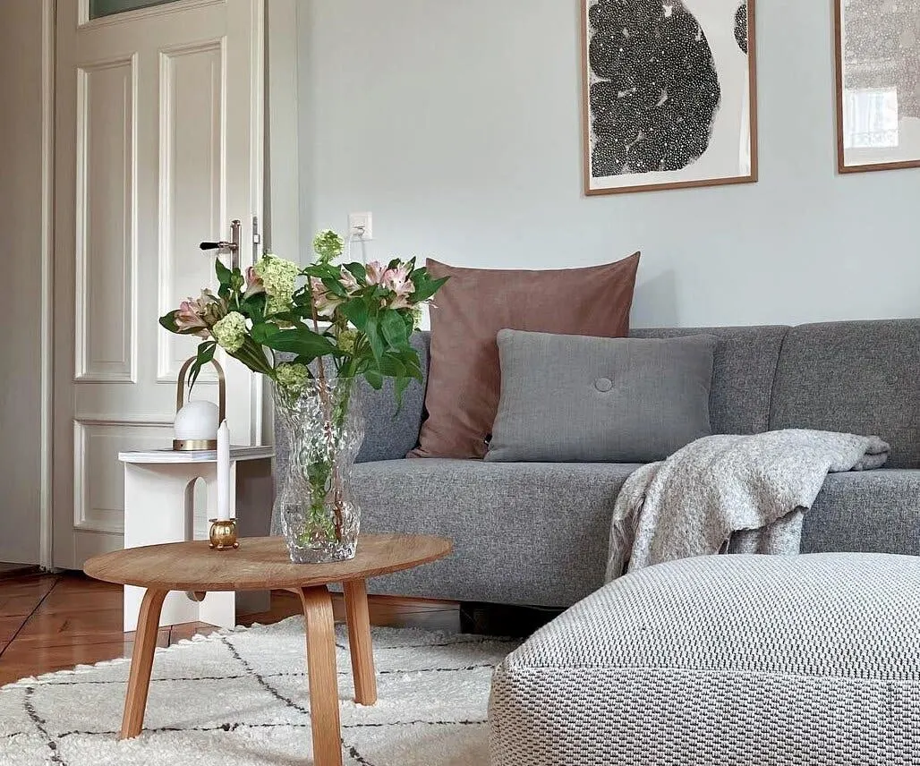 Durchsichtige Vase mit Schnittblumen auf einem braunen Holztisch als natürliche und frische Deko im Wohnzimmer