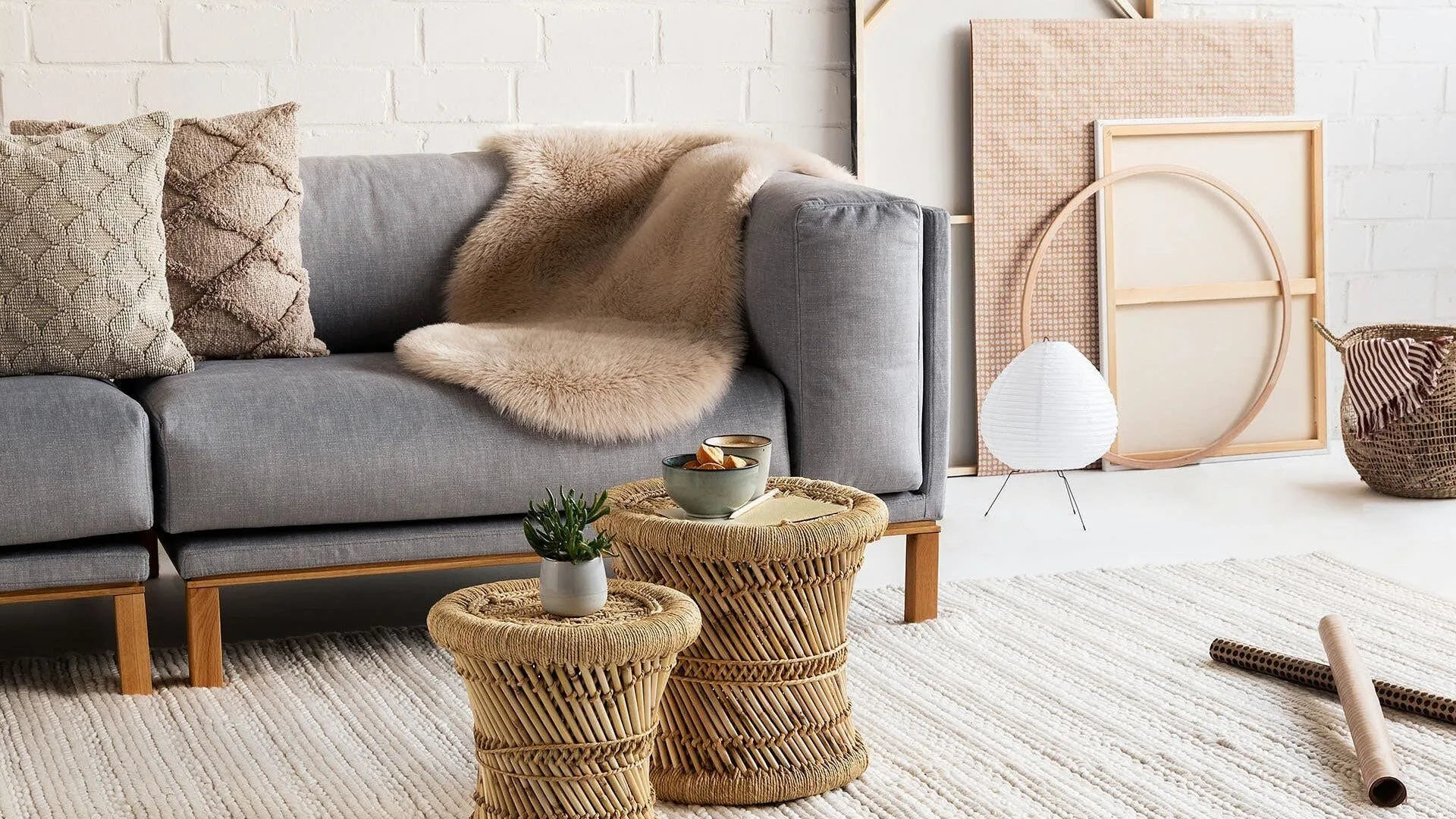 Natürliches Wohnzimmer in Erdtönen wie Braun, Grau und Beige mit einem Couch-Tisch aus Bast und einer Sukkulente als dekoratives Element