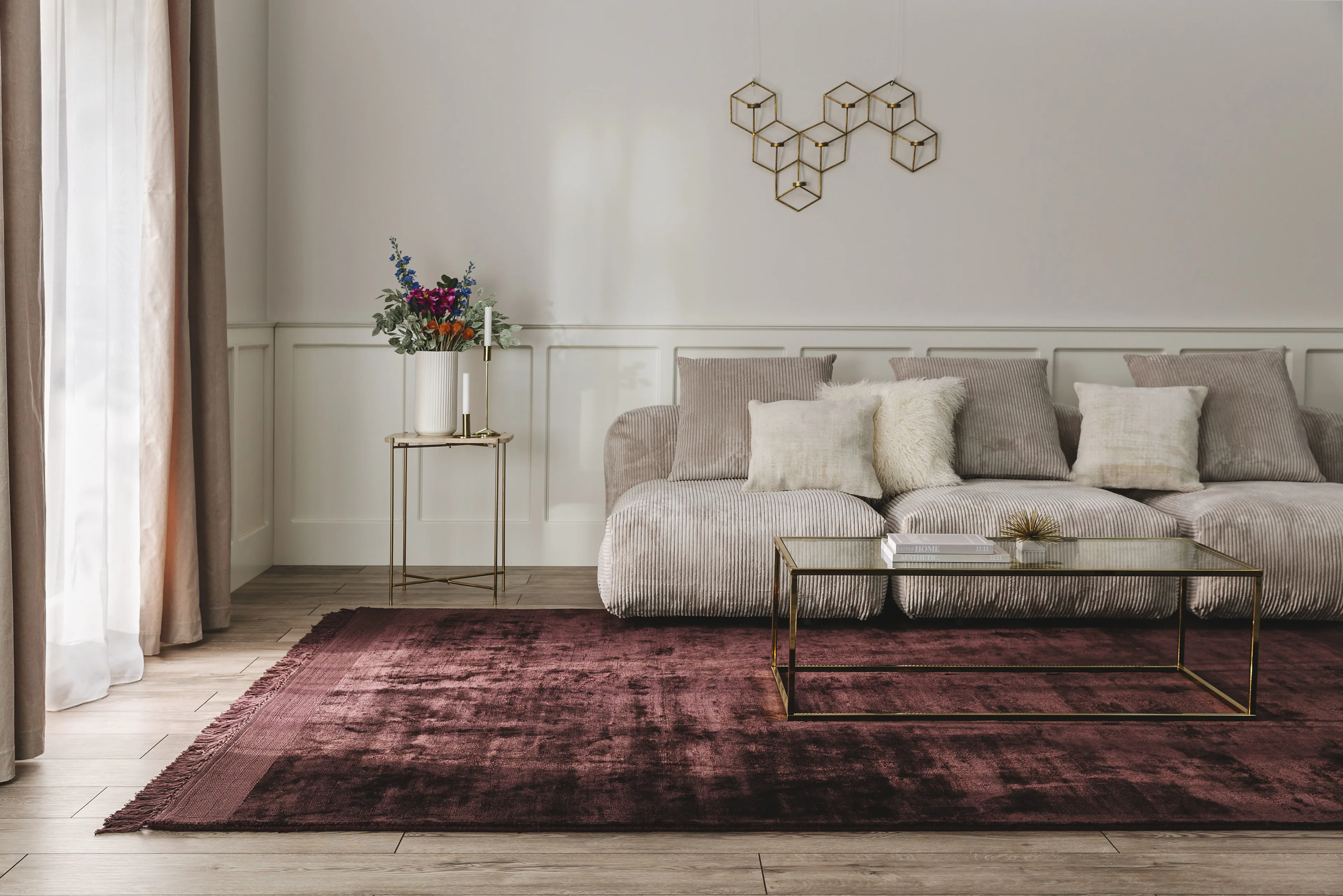 Gereinigter, beerenroter, großer Teppich aus Viskose im Wohnzimmer unter einem großen Cordsofa mit Couch-Tisch aus Glas