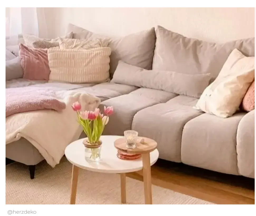 Frühlingshafte Schnittblumen auf einem weißen, runden Couch-Tisch in einem Wohnzimmer in Rosa