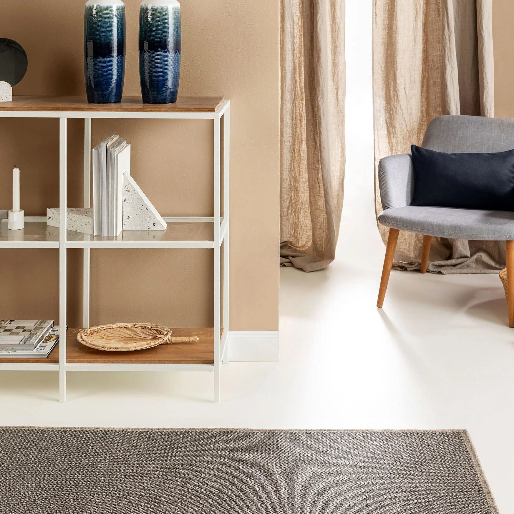 Minimalistisches Wohnzimmer mit Regal aus weißem Metall und einem grauen Sessel für einen Look im reduzierten Japandi