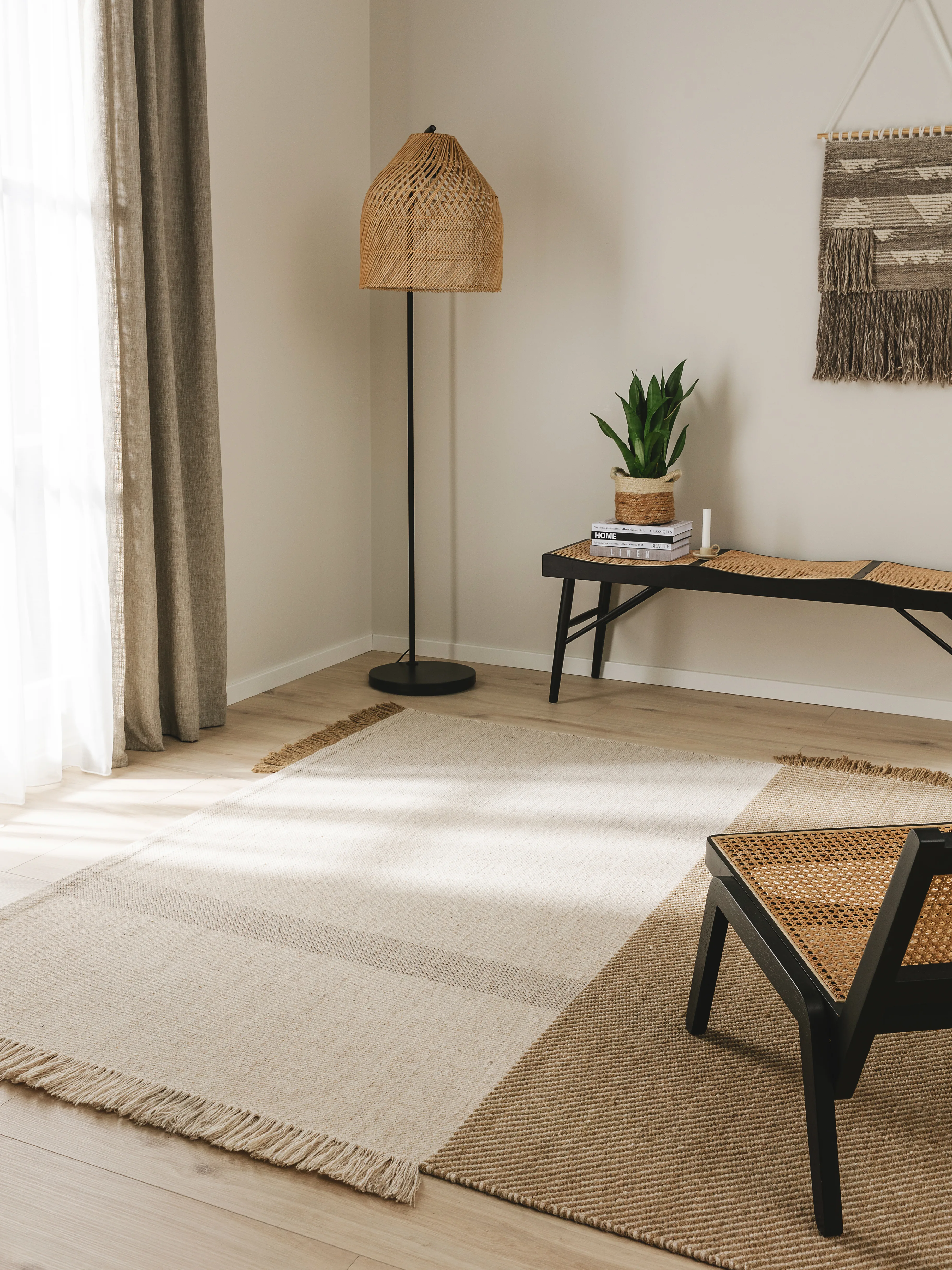 Skandinavische Einrichtung im Wohnzimmer mit vielen Naturtönen und natürlichen Materialien wie Lampe mit Rattanschirm und Rattansessel