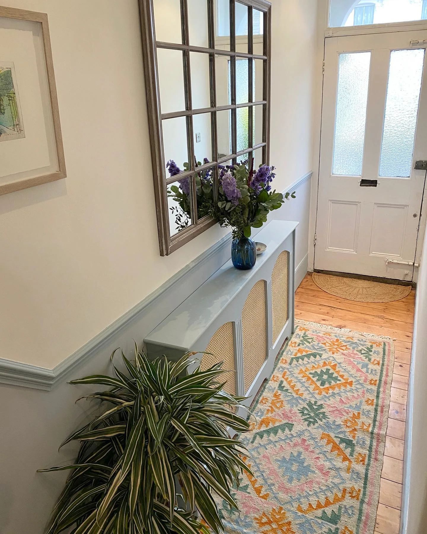 Bunt gestalteter Flur mit schmalem Sideboard in Mintgrün, mintgrünem Treppengelände und grün-orangenem Läufer in einer Altbauwohnung
