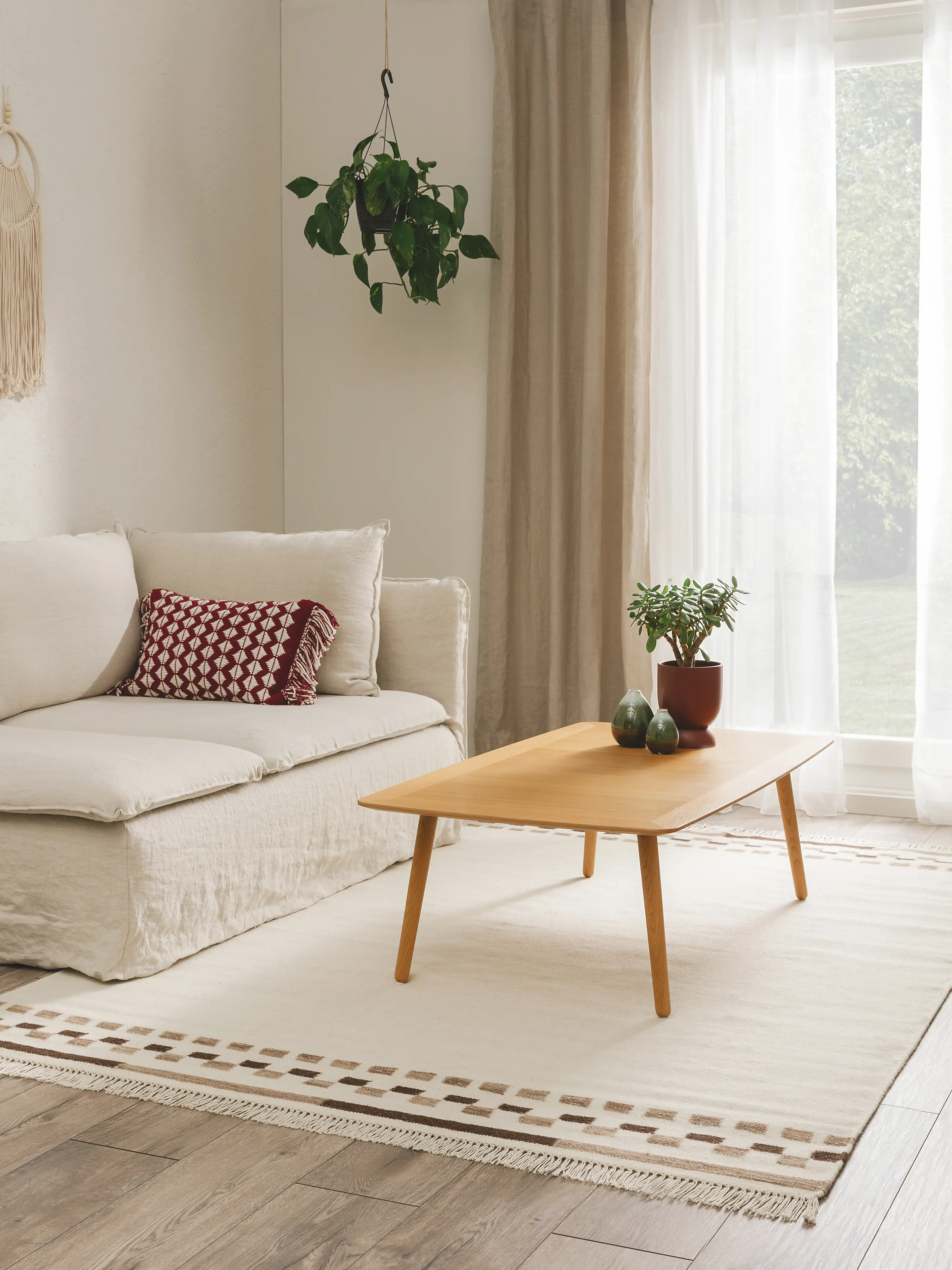 Fußbodenheizung geeigneter Wollteppich mit Fransen im Wohnzimmer unter einem Zwei-Sitzer-Sofa und einem Couch-Tisch aus Holz