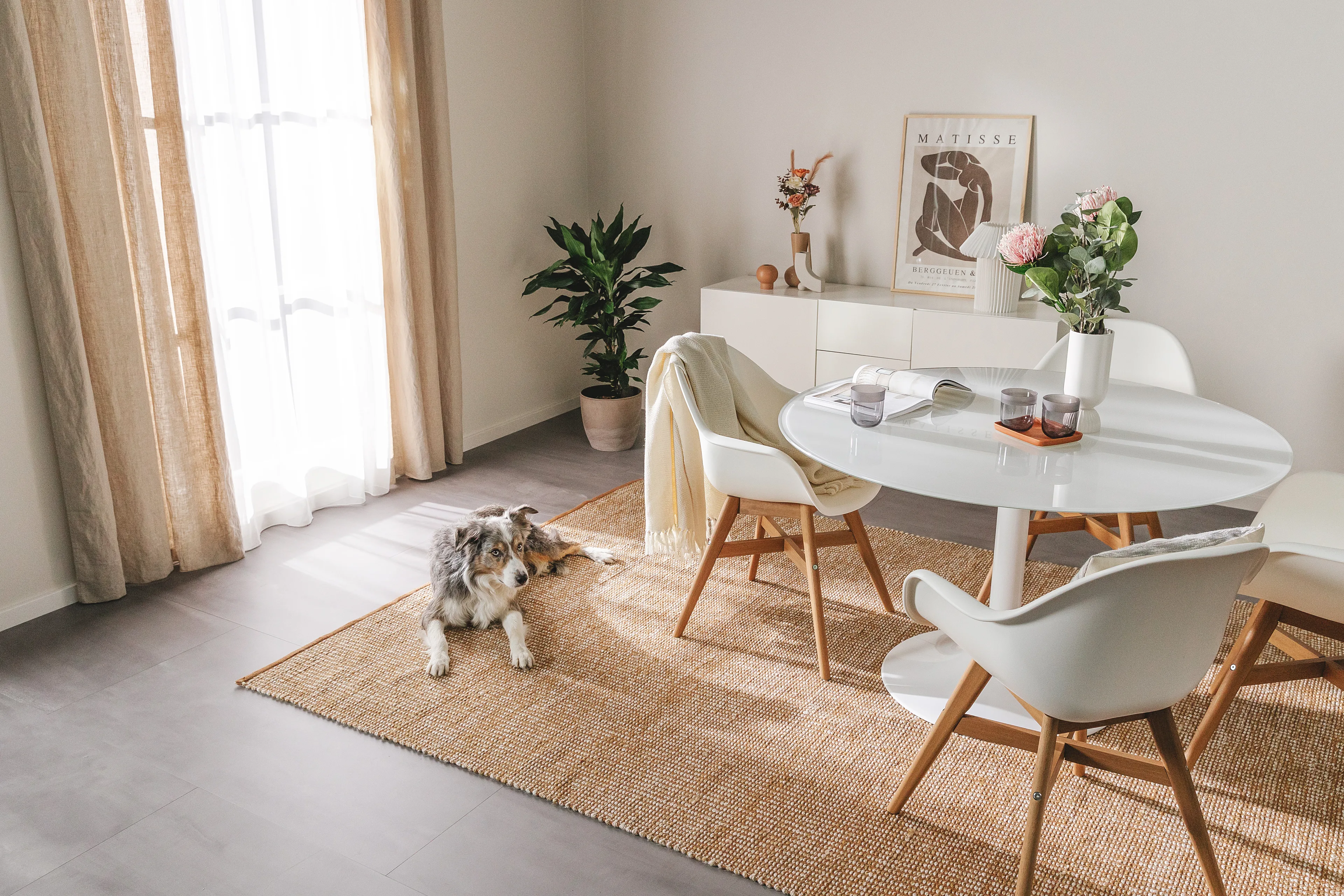 Helles Esszimmer im Skandi-Style mit einem Juteteppich, auf dem ein großer Hund liegt