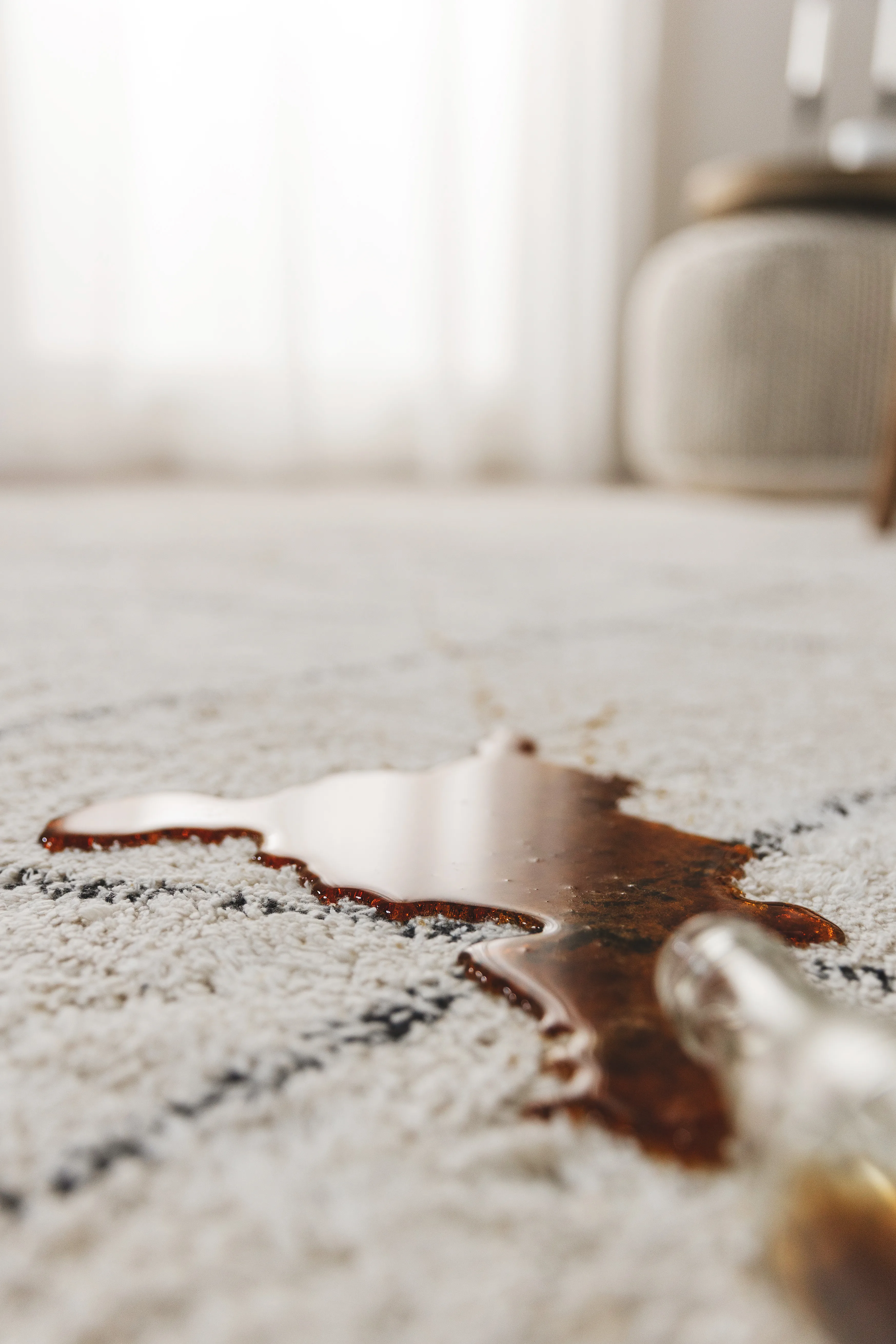 Detailaufnahme von einer ausgelaufenen Colaflasche auf einem beigen Teppich