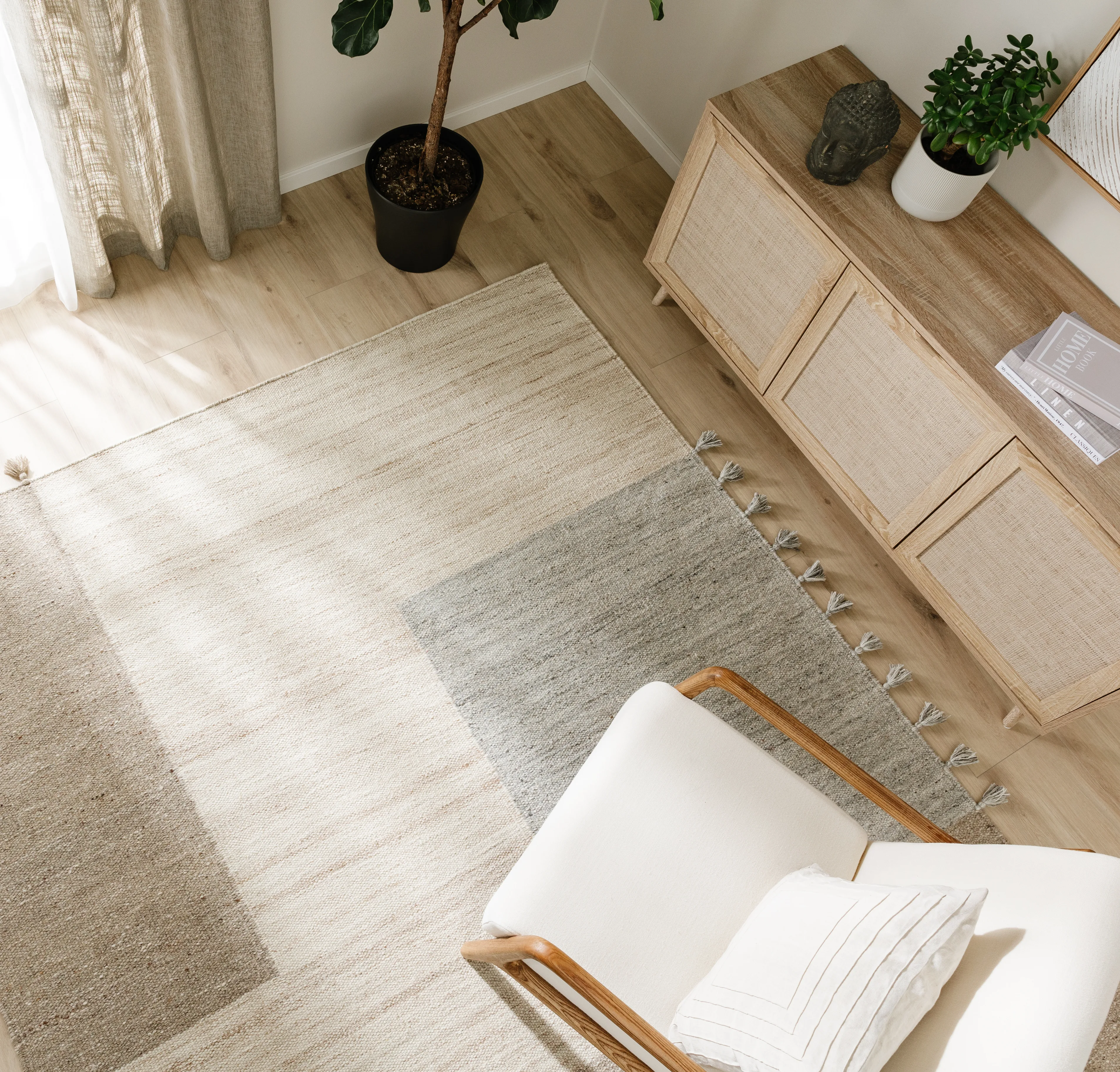 Skandinavisch eingerichtetes Wohnzimmer mit Teppich, Sessel und Sideboard in hellen und natürlichen Tönen