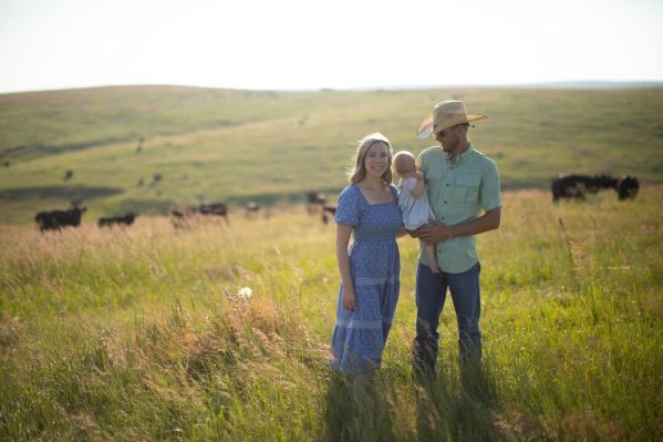 Image of family standing in a pasture with cattle.