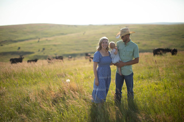 Image of family standing in a pasture with cattle.