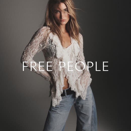 Model wearing a white ruffled top with lace sleeves and jeans. 