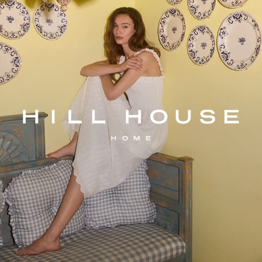 Model relaxing on a daybed in a white maxi dress with a ruched waist.