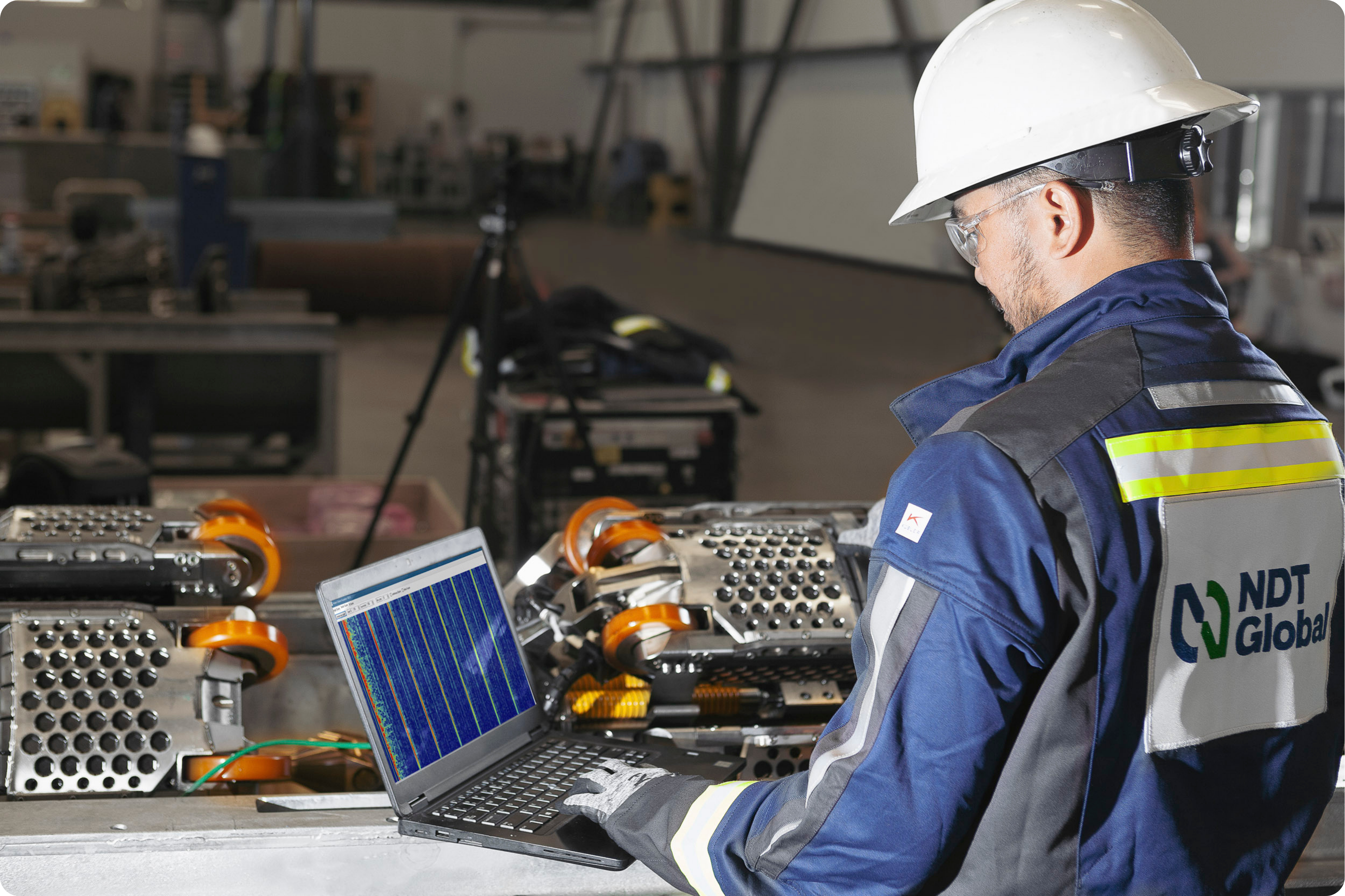 NDT Global Employee working on laptop next to PROTON Tool