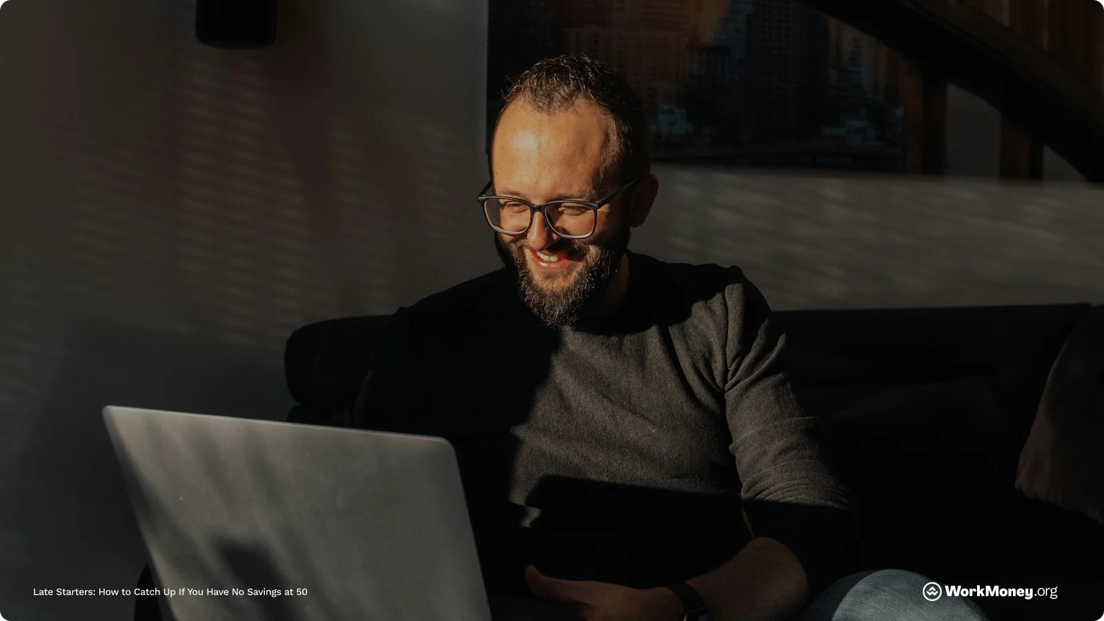 A man sits smiling looking at his computer.