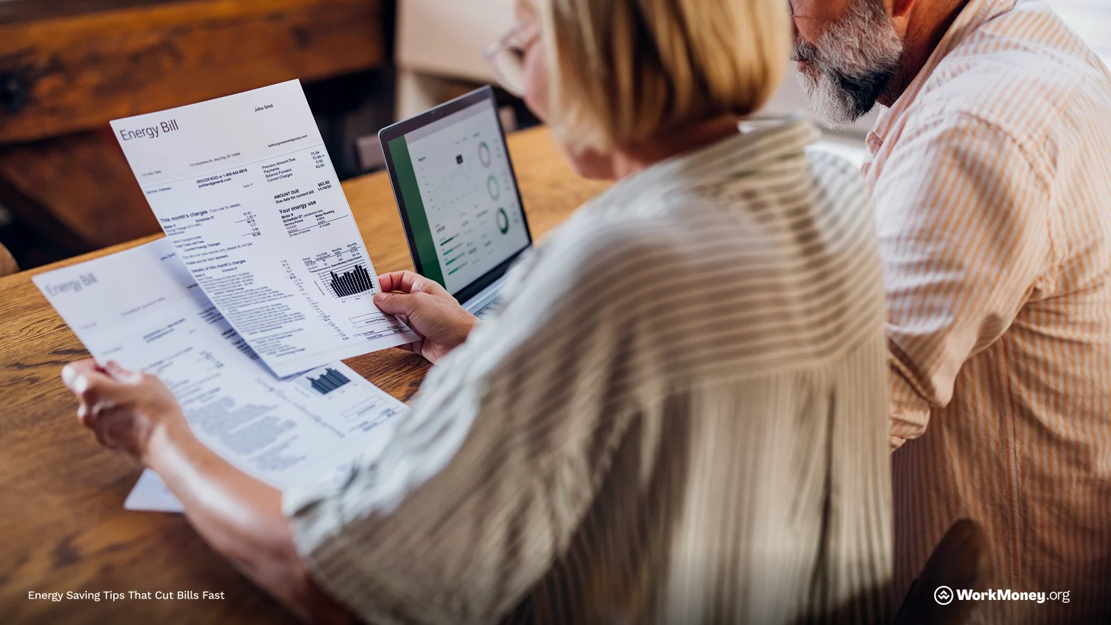 Two older adults sitting at a table reviewing printed energy bills. One person holds a paper with charts labeled “Energy Bill,” while a laptop nearby displays utility usage graphs. The scene suggests analyzing home energy costs. Text in the corner reads “Energy Saving Tips That Cut Bills Fast.”