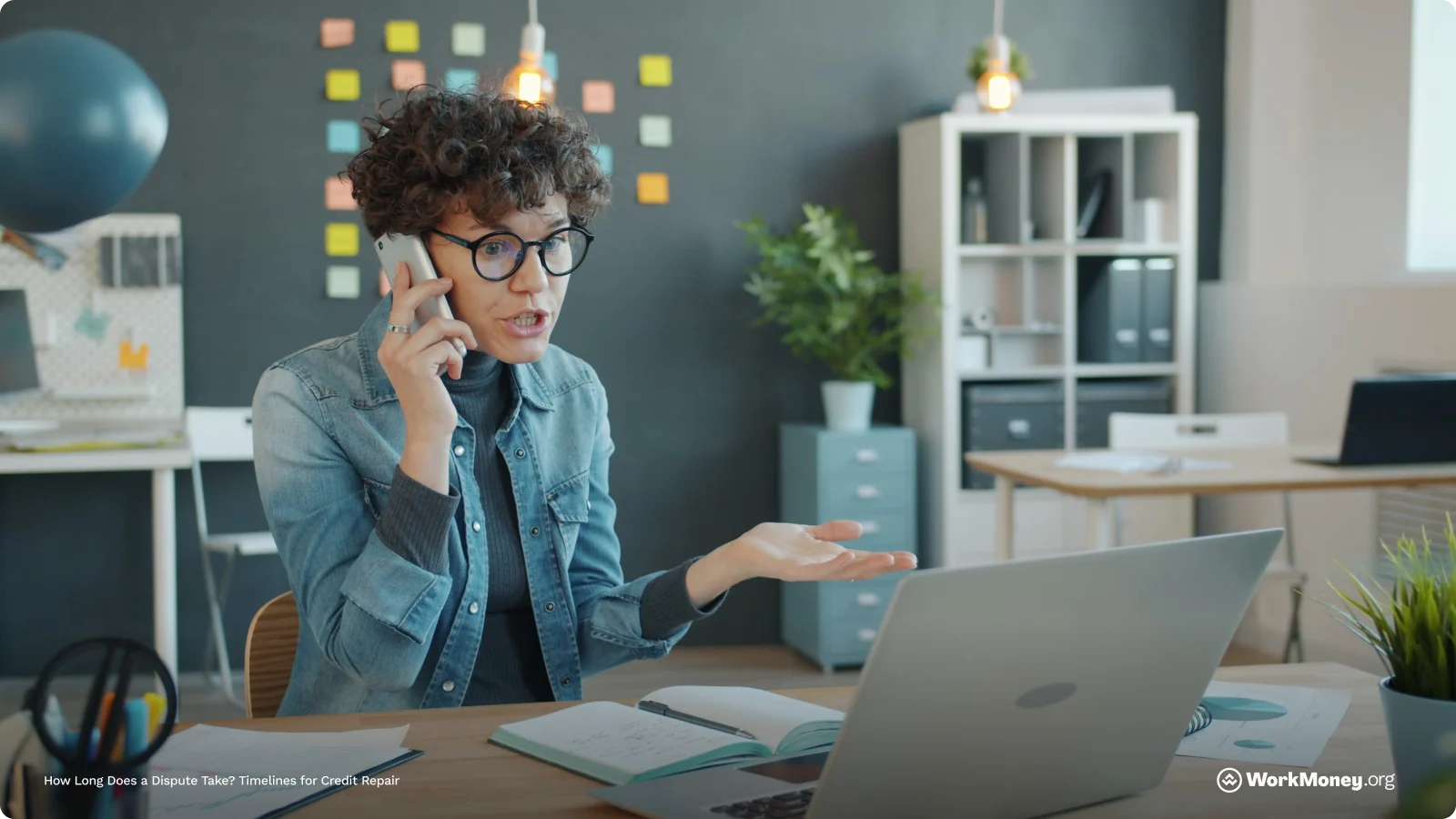 A woman talks on the phone sitting at her desk.