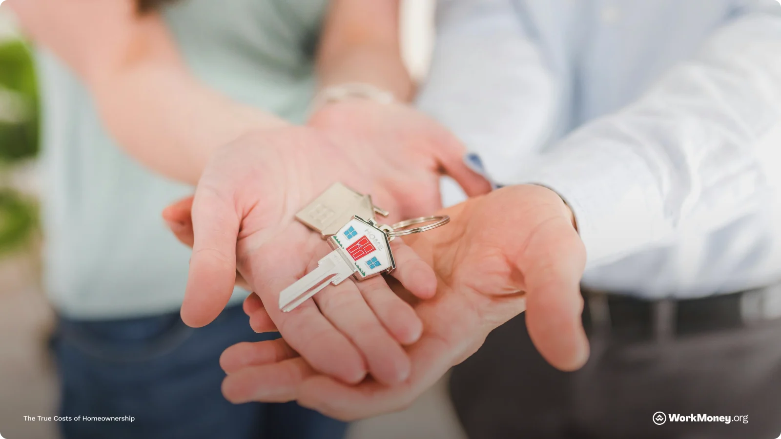 Couple holding house keys in their hand with a little home keychain attached.