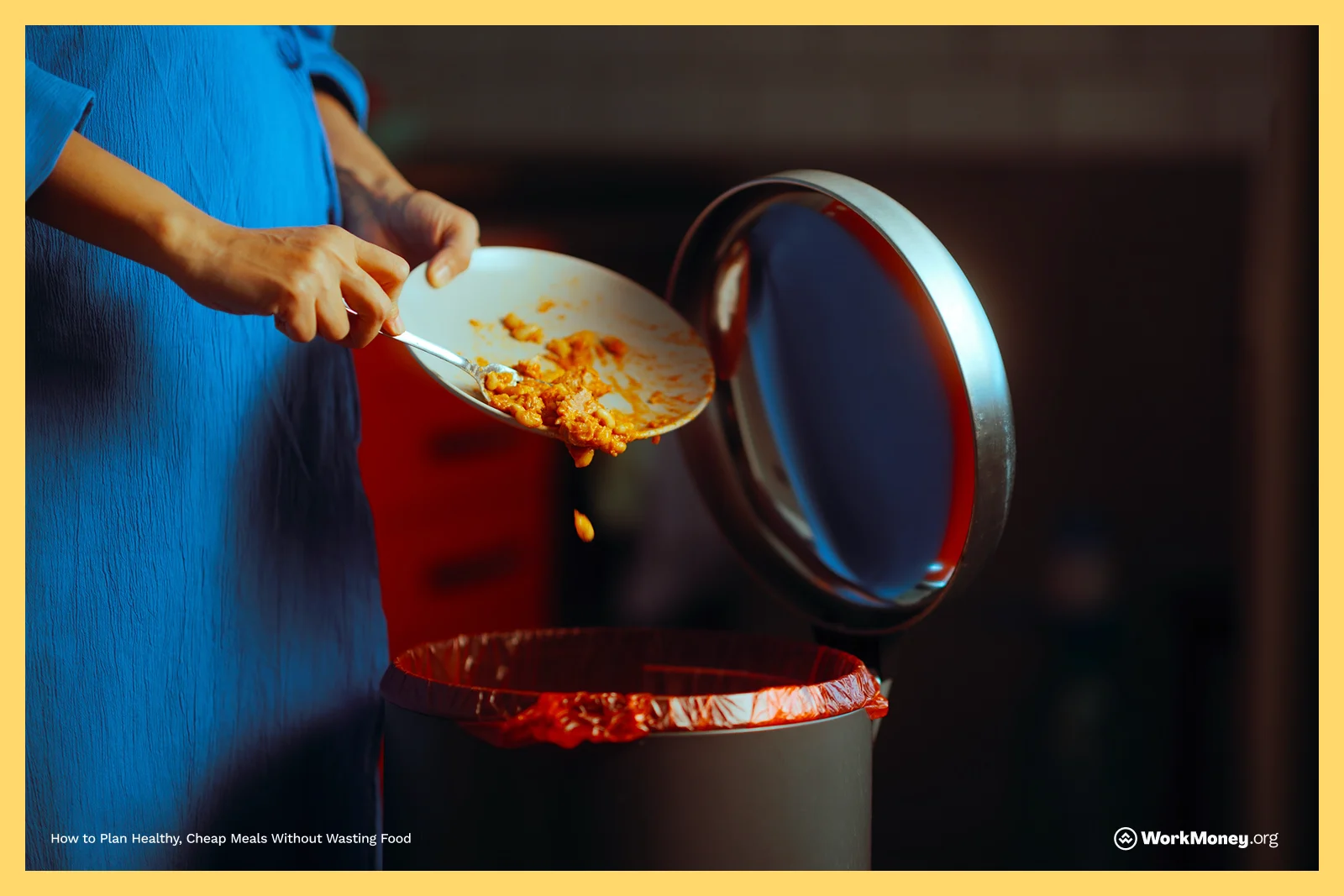 Person in a blue shirt scraping uneaten food from a white plate into a trash can lined with a red garbage bag.