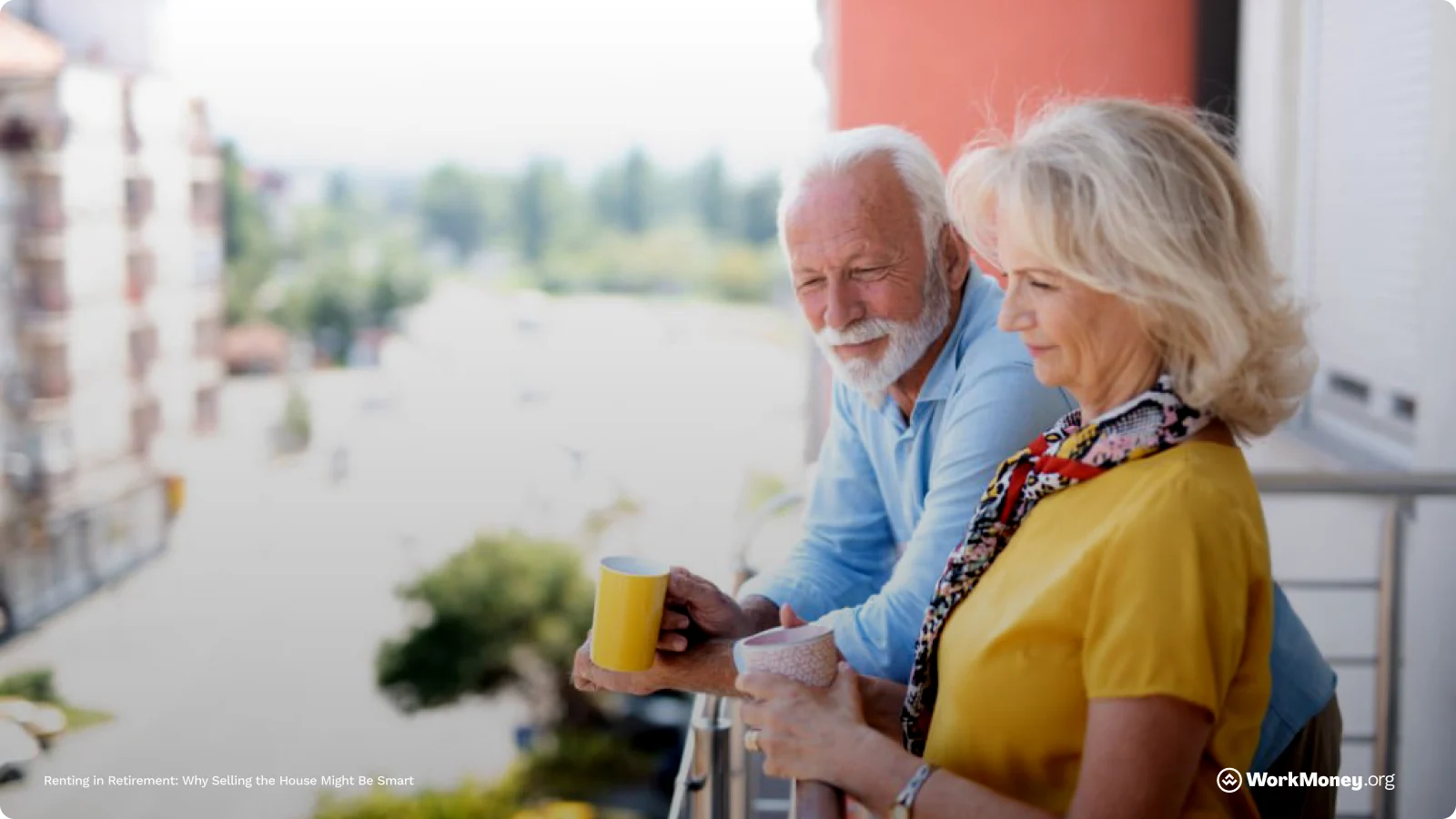 A couple look happily onto a street from their balcony
