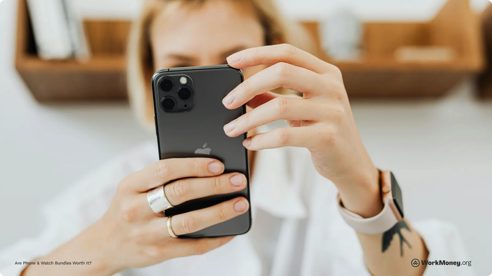 Woman looks at her iPhone while wearing an Apple watch.