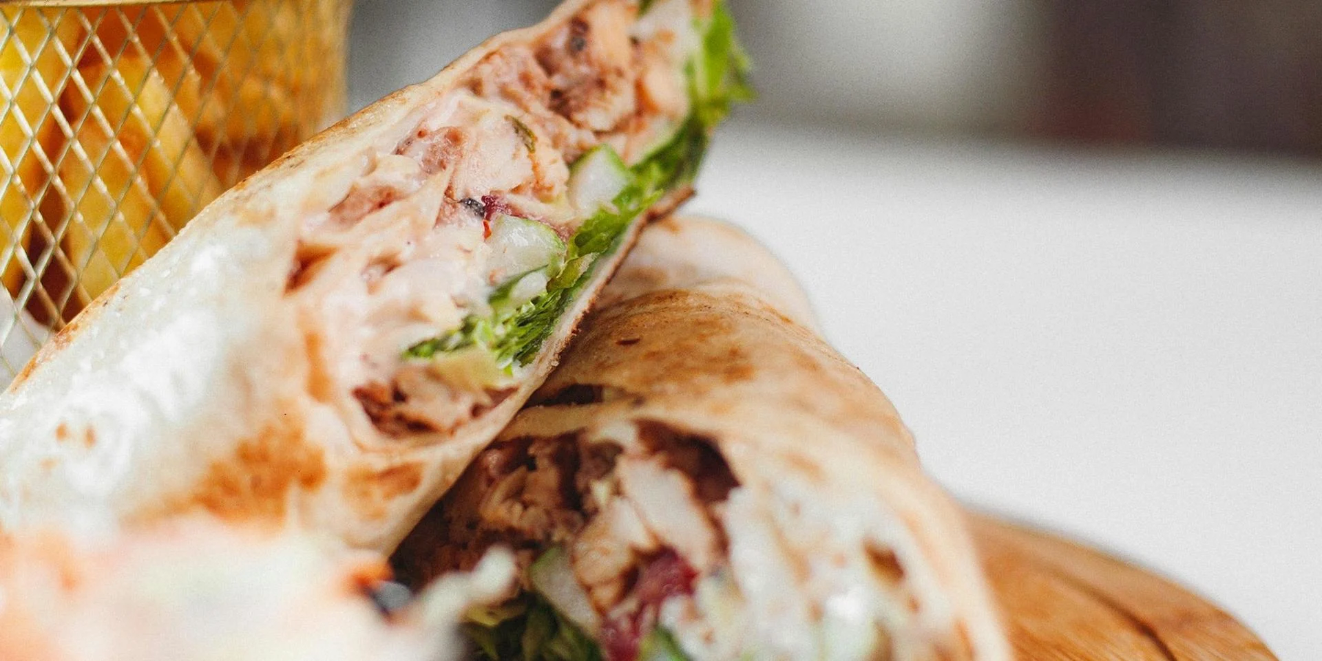 A chicken caesar wrap cut in half on a plate.