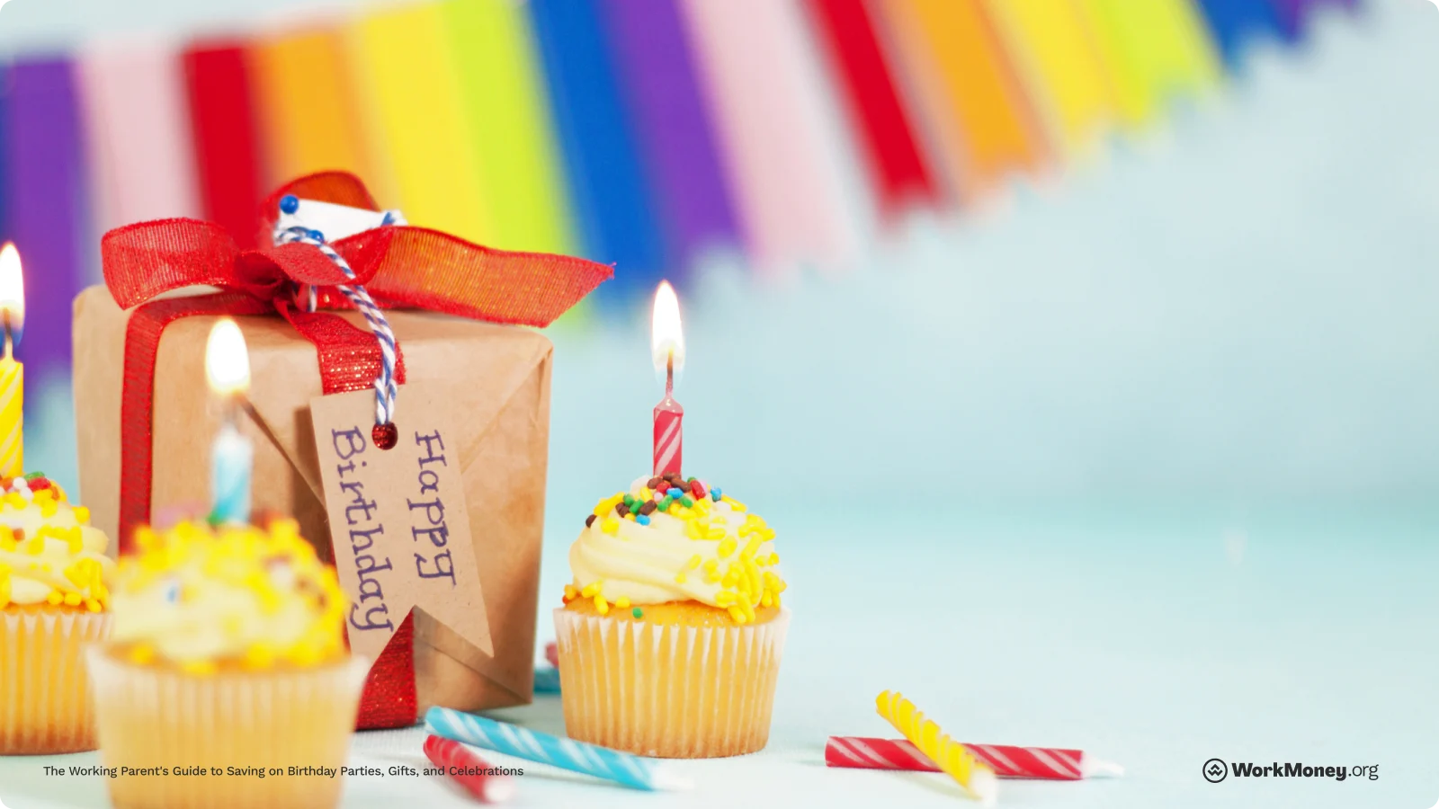 A present sits next to birthday cupcakes on a table.