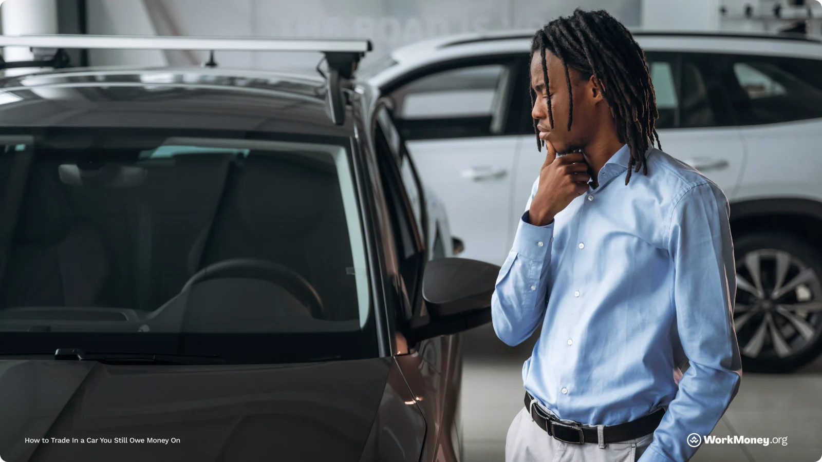 A man studies a car on a car dealership lot.