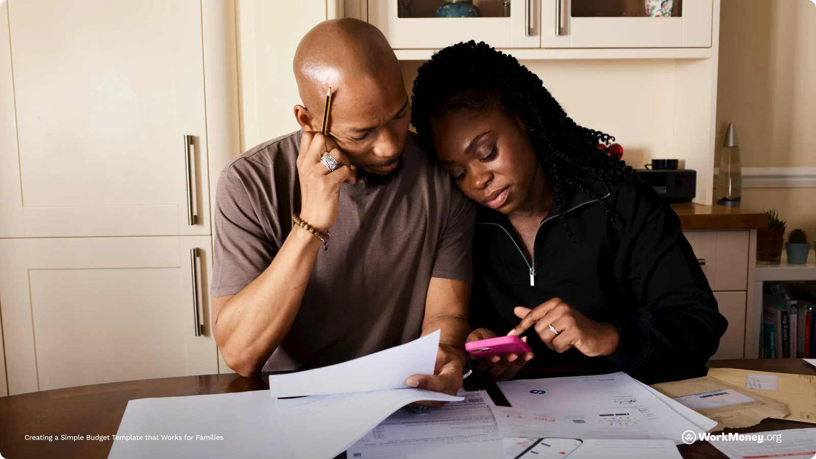 A couple look stressed at a calculator in front of some family bills.