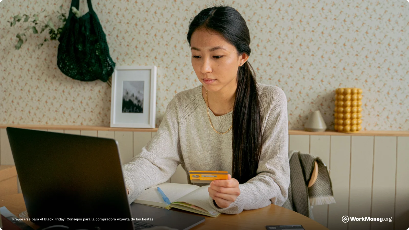 Woman sitting at computer holding a credit card