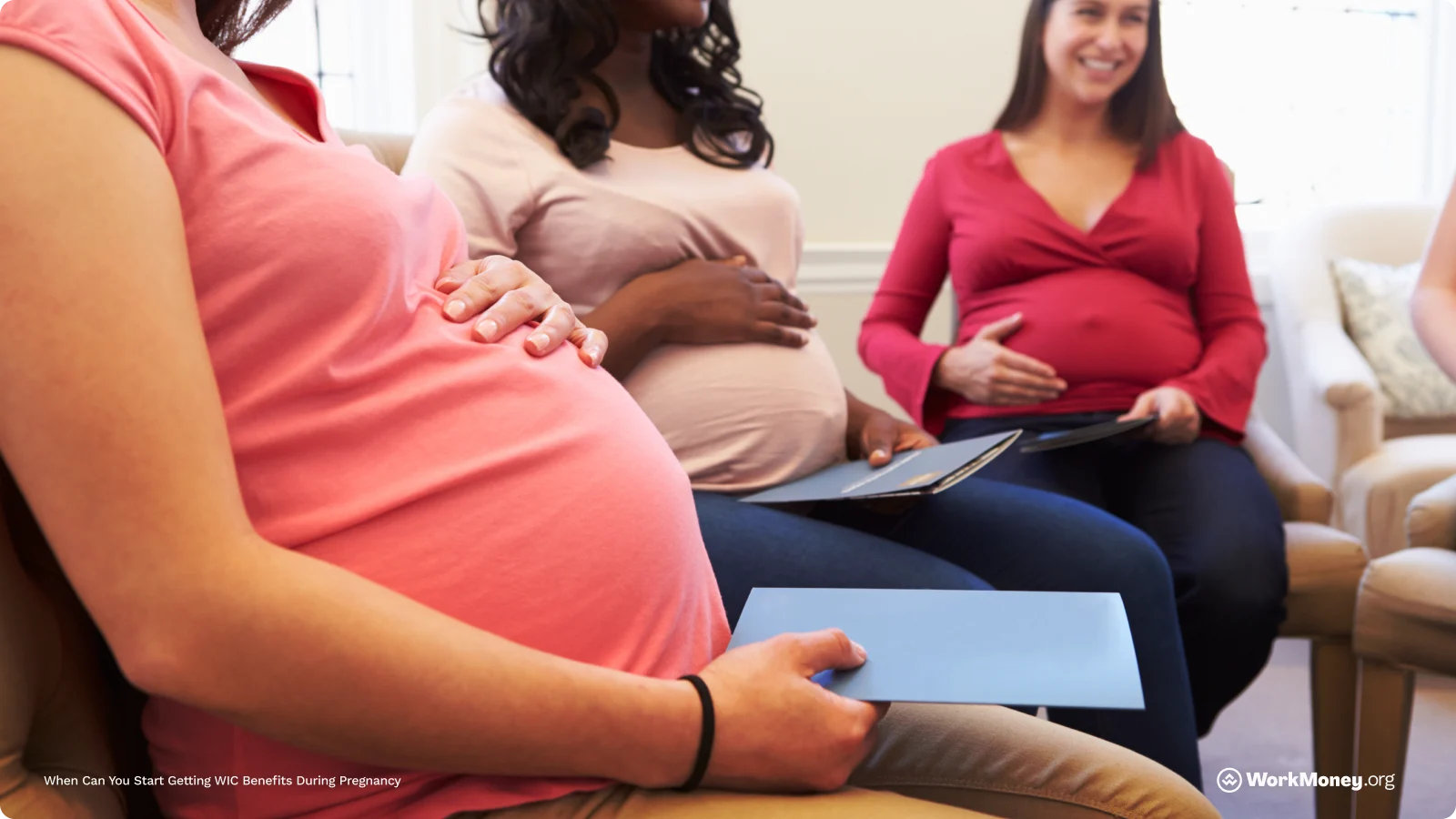 Woman sits in waiting room holding her pregnant belly.
