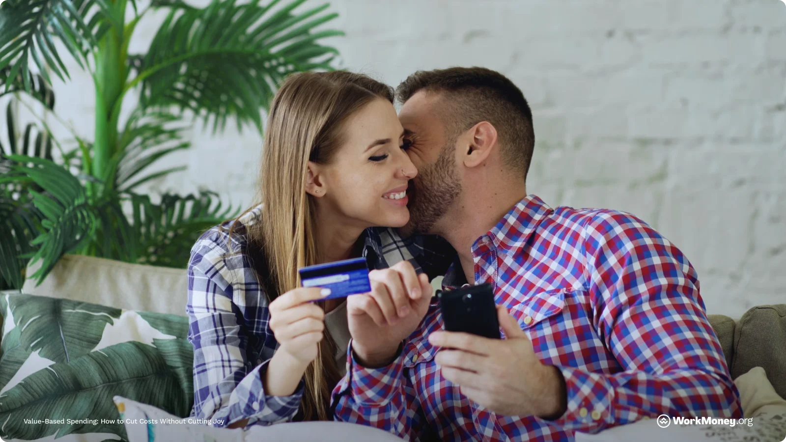 A couple smiles while the woman holds a credit card