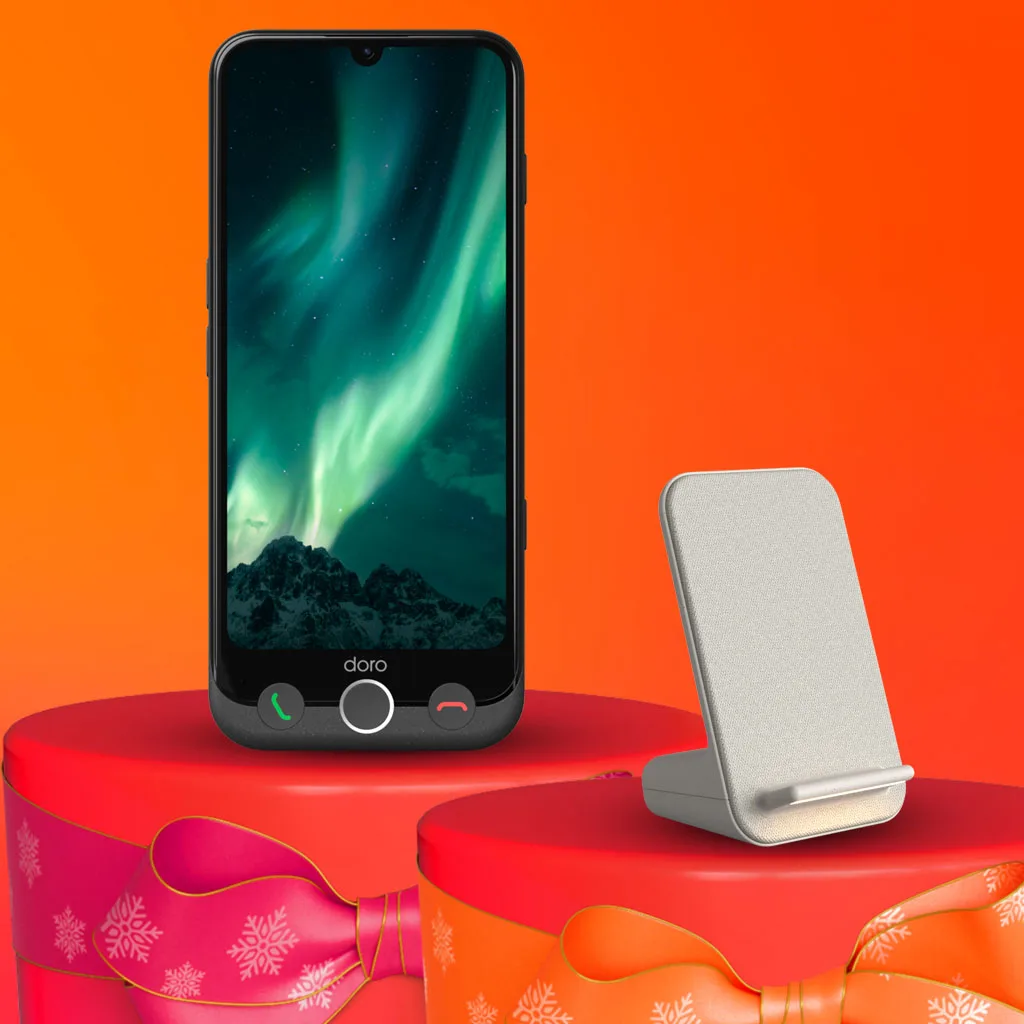 Smartphone med norrsken på skärmen och en laddningsställning på röda presentaskar mot en orange bakgrund.