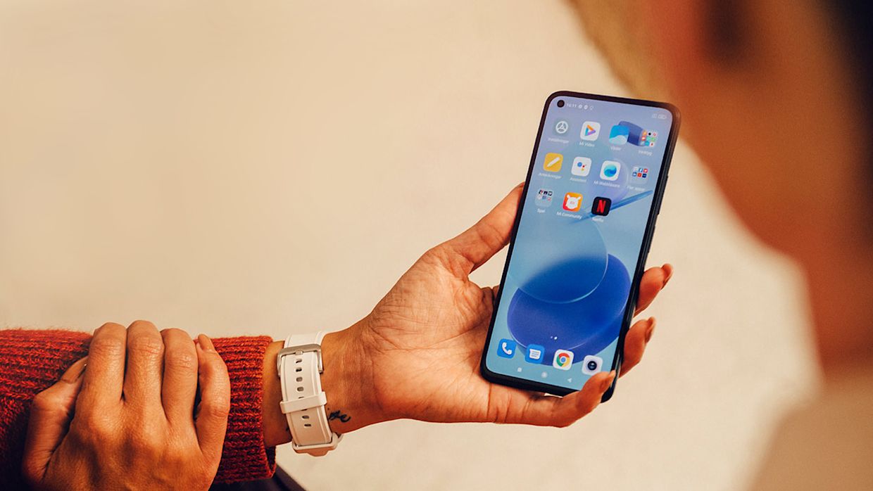 En person med röd stickad tröja sitter och tittar i sin mobil