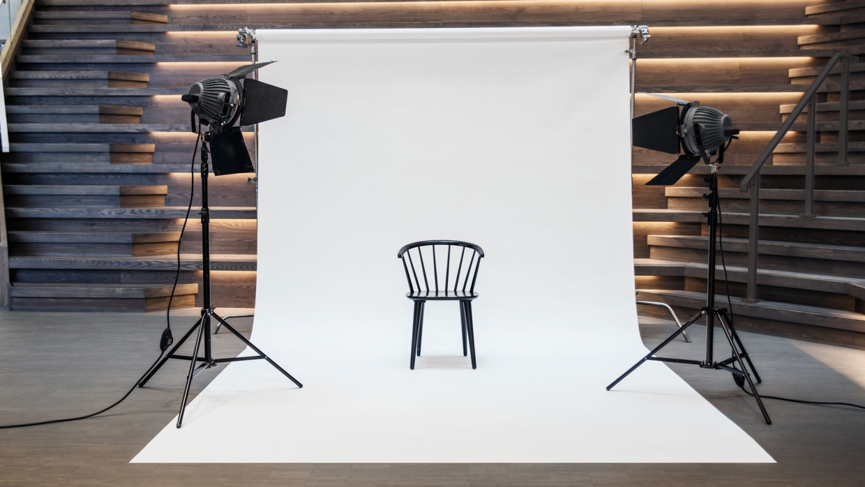 En stol mot vit fotoduk. Två fotolampor riktade mot stolen.