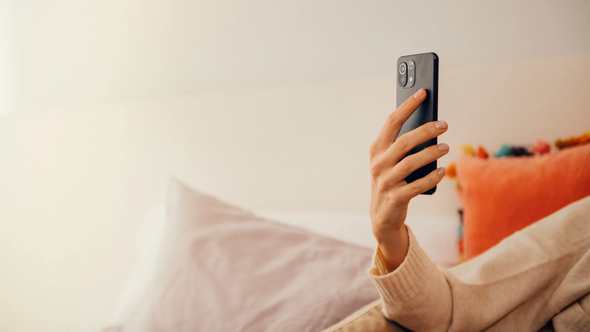 En person i beige tröja håller i en mobil.