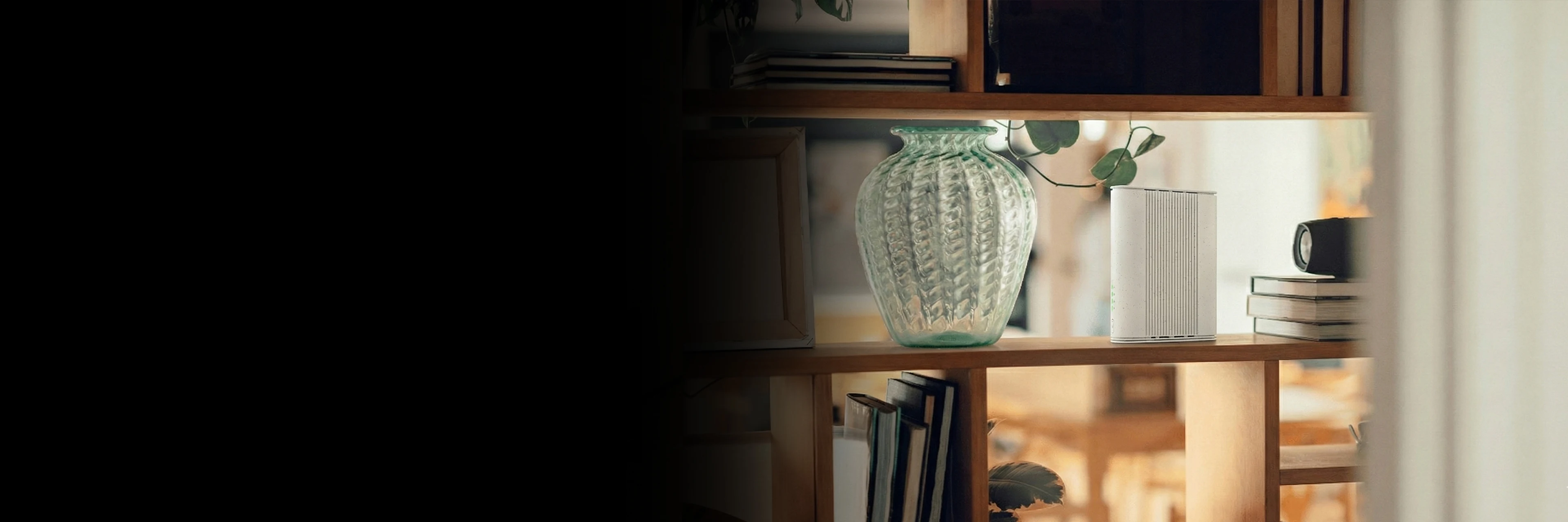 A wooden shelf with a router, books, and a small speaker, set against a blurred background.