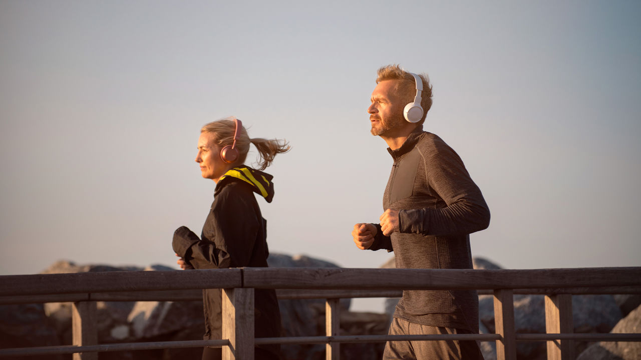 Man och kvinna joggar tillsammans. Båda har hörlurar på.