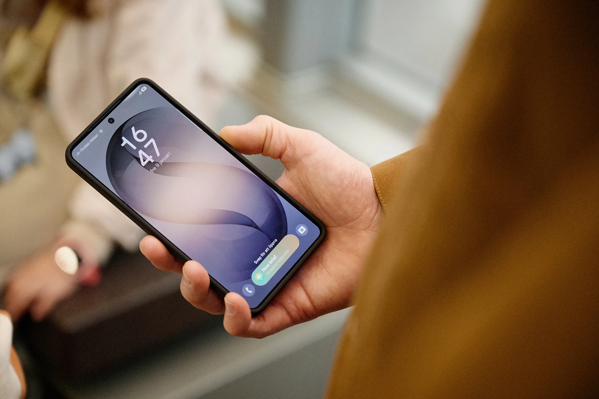 Hand som håller en smartphone med låsskärm inomhus