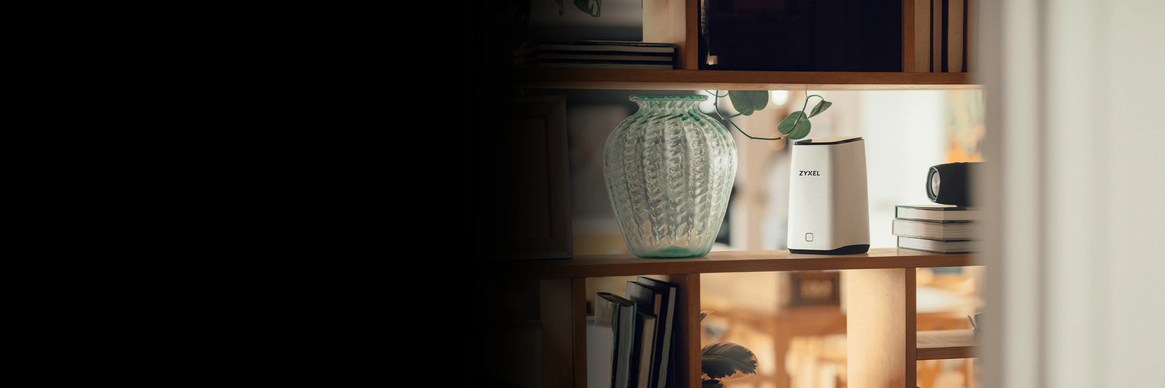 Glashylla med en stor grön vas, en vit Zyxel-router och böcker. Bakgrunden är suddig med varma färger.