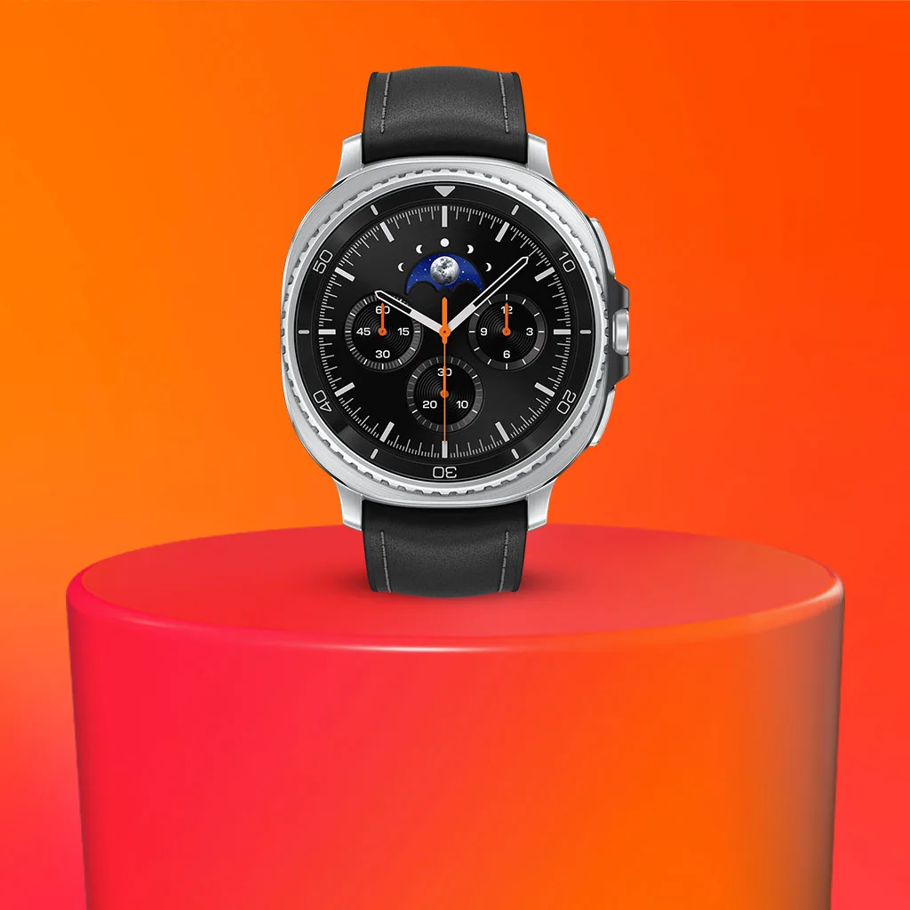 Galaxy watch 8 Classic med svart läderarmband på en röd cylinder mot orange bakgrund. Klockan har en svart urtavla med flera visare.