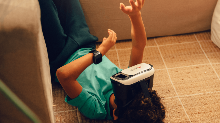 Ett barn med grön tröja ligger på golvet med VR-glasögon på sig