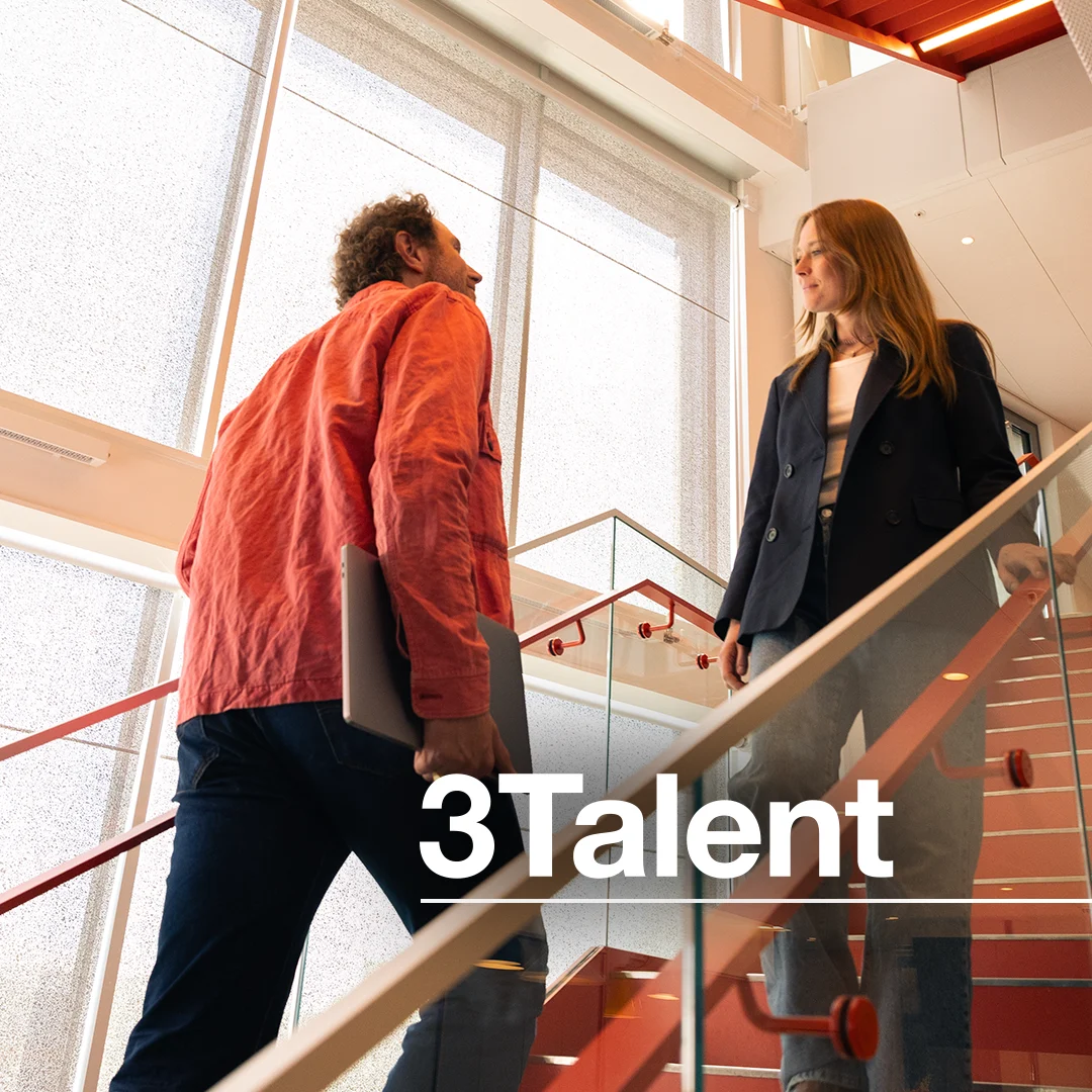 En tjej i svart kavaj möter en kille i röd jacka i en trappa.