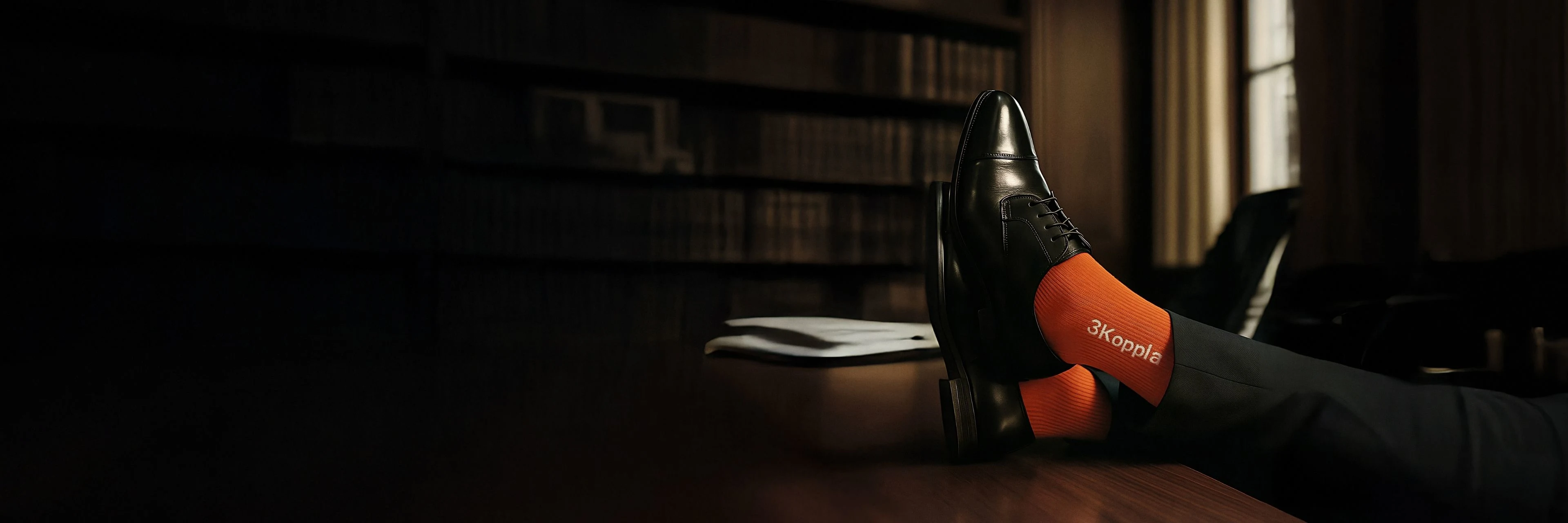 En person med svarta skor och orange strumpor vilar fötterna på ett bord i ett bibliotek. På de orange strumporna är det en 3Koppla logga i vitt. Texten: "Det finaste man kan ge är lite mer" står under fötterna.