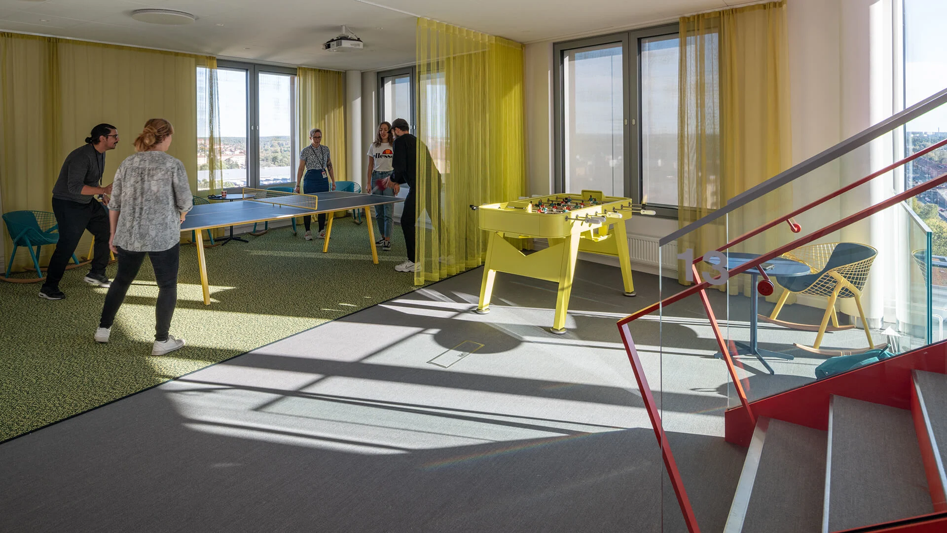 Fem personer spelar pingis i ett färgglatt kontor.